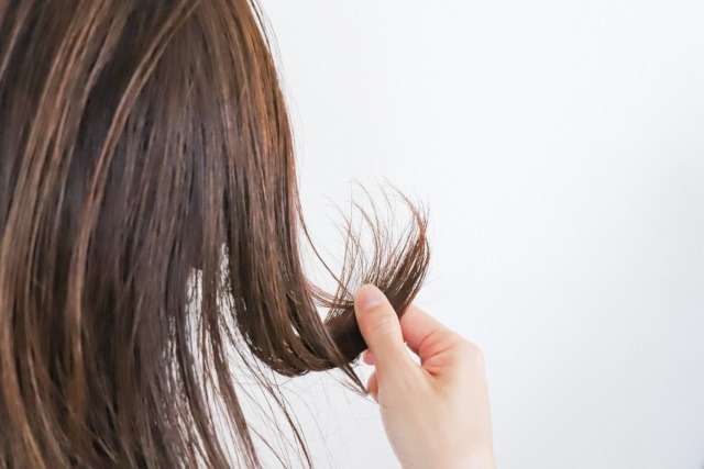 髪のダメージ・枝毛・切れ毛を確認する女性